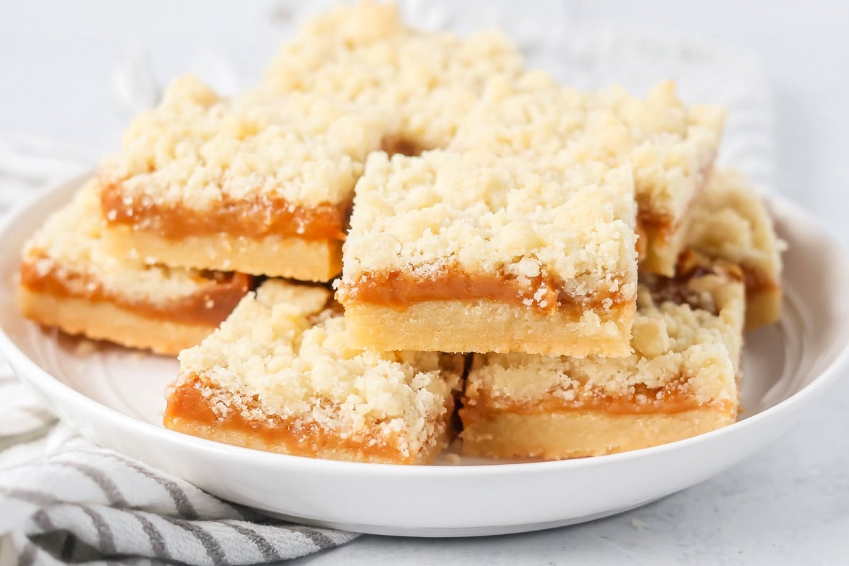 Salted caramel cookie bars stacked on a white plate.