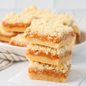Three stacked salted caramel cookie bars on parchment paper.