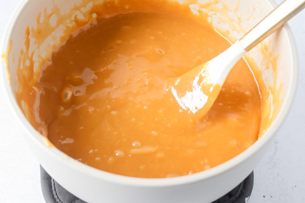 A bowl of melted caramel for salted caramel cookie bars.