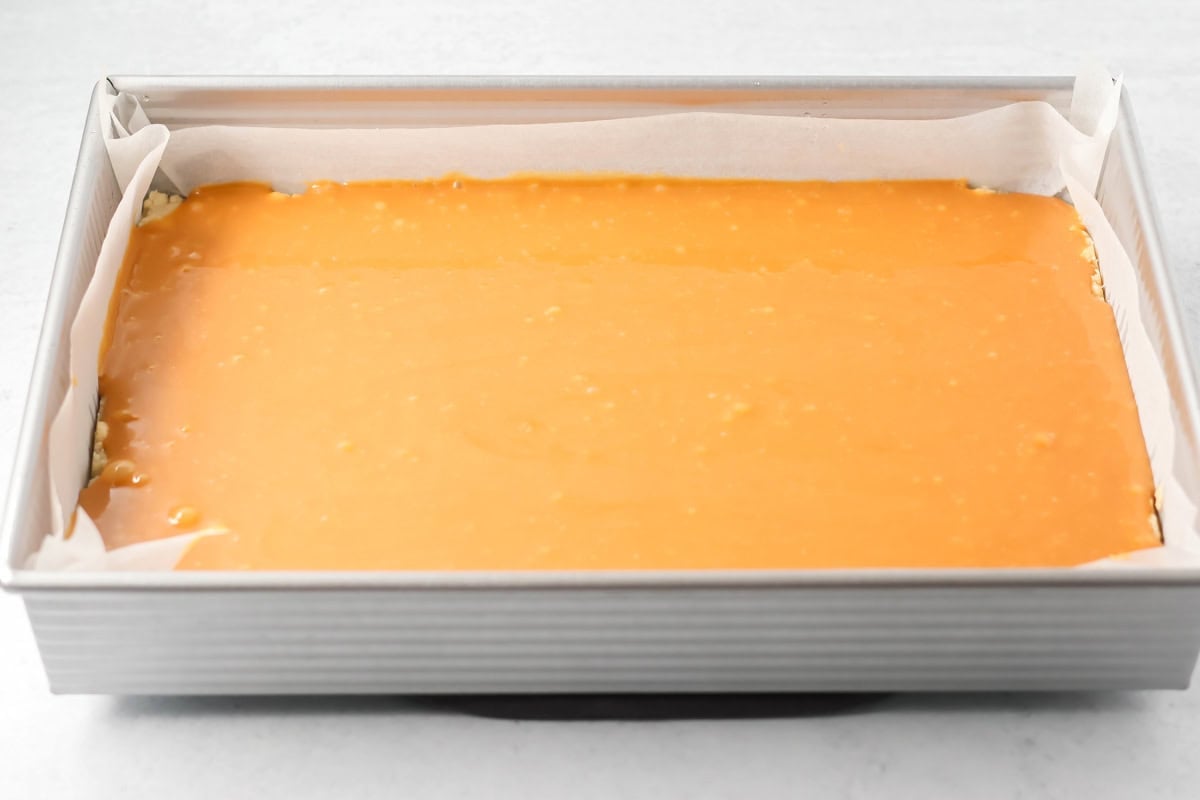 Adding caramel to salted caramel cookie bars.