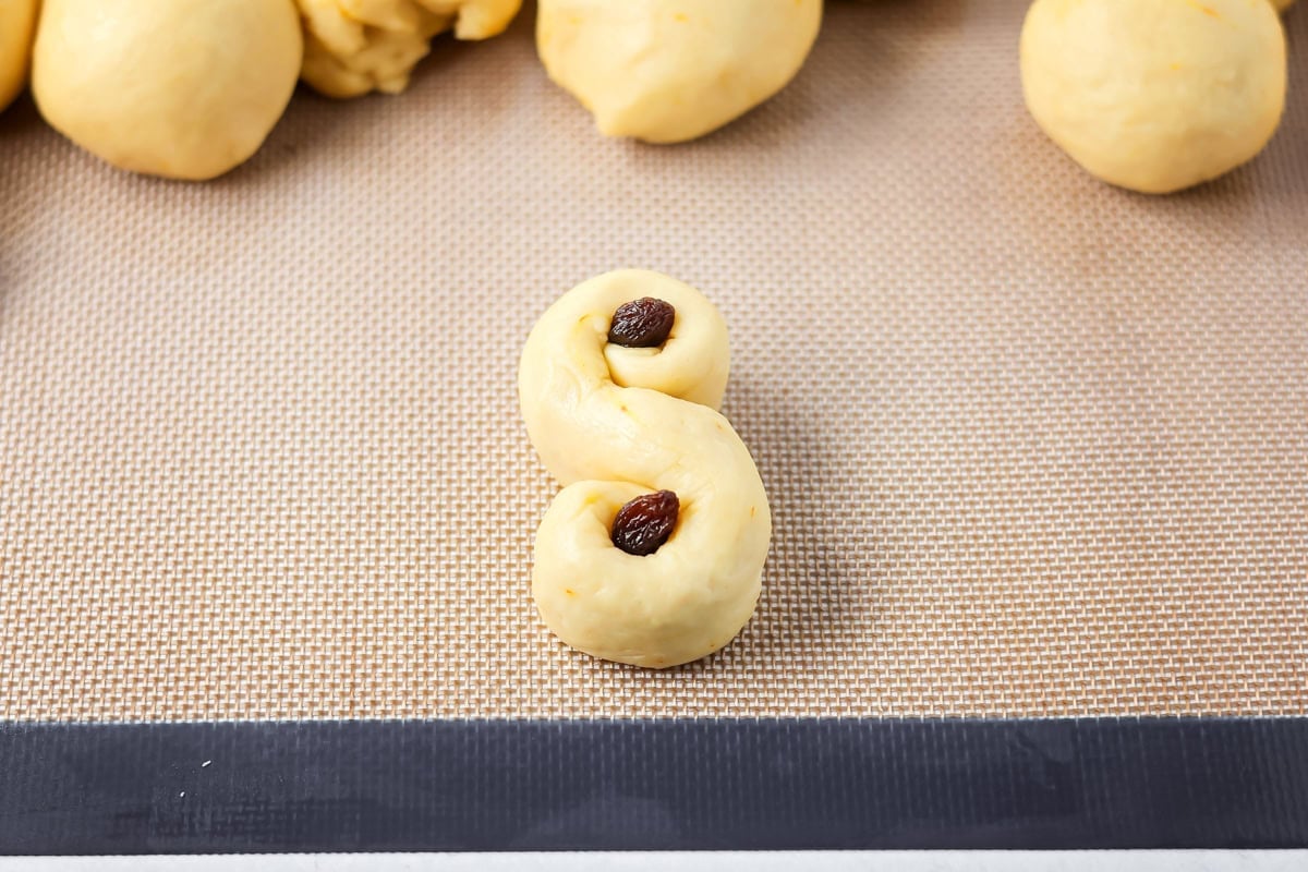 Topping St. Lucia Buns with raisins.