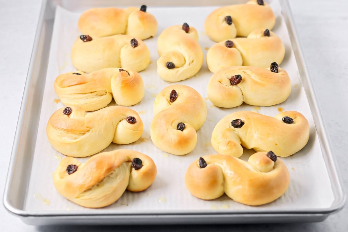 St. Lucia Buns topped with raisins on a baking sheet.