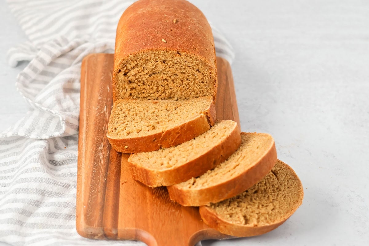 Sliced limpa bread on a wooden cutting board.