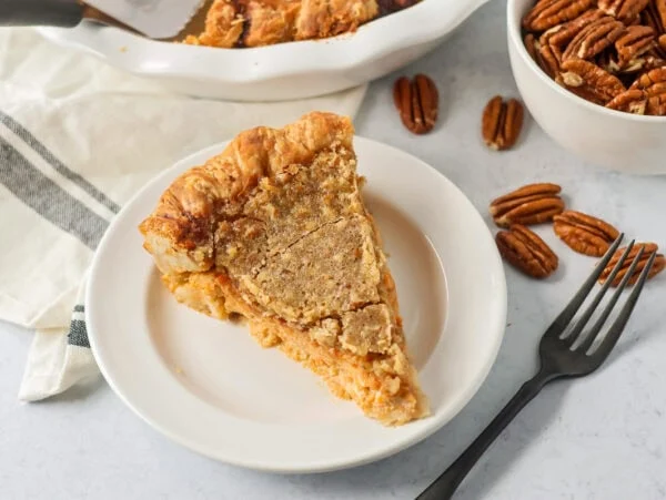 A slice of sweet potato pecan pie on a white plate.