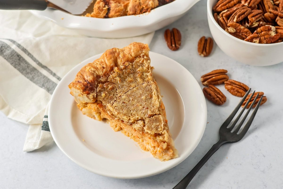 A slice of sweet potato pecan pie on a white plate.