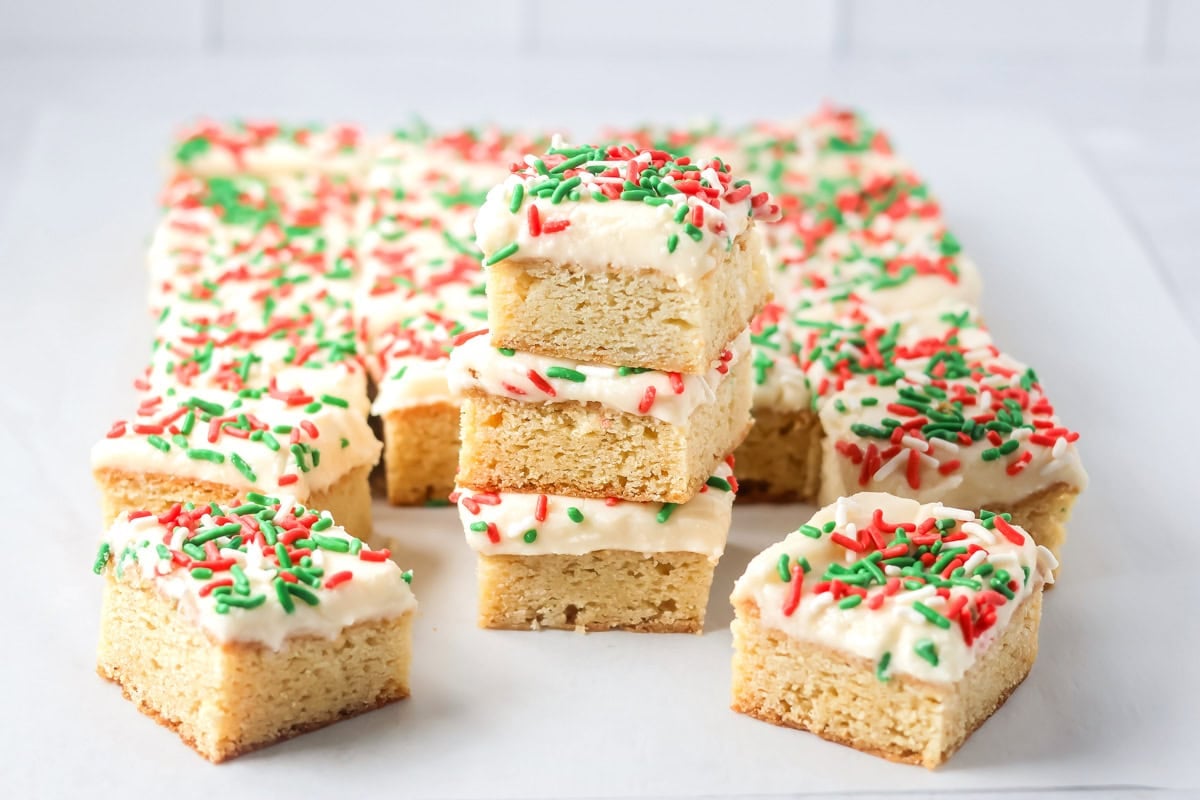 Christmas sugar cookie bars squares topped with frosting and sprinkles.
