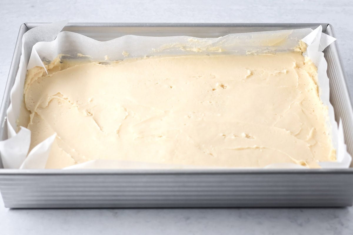 Christmas sugar cookie bars batter spread in a baking dish.