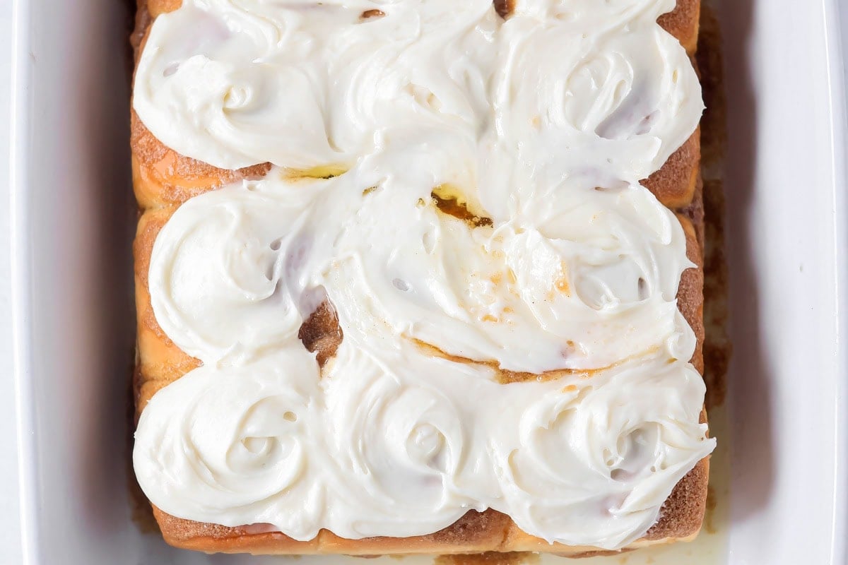 Spreading frosting on Hawaiian king cinnamon rolls.