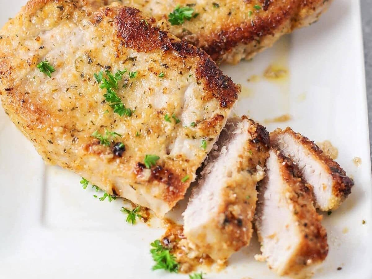 Parmesan crusted pork chops baked and cut on white dish.